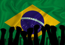 Brazil – Bolsonaro Towards a Military Dictatorship – Worse than 80 Years Ago Silhouette of raised arms and clenched fists on the background of the flag of Brazil. The concept of power, power, conflict. With place for your text. Brazil military conflict
