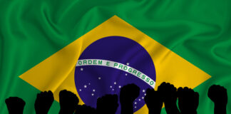 Silhouette of raised arms and clenched fists on the background of the flag of Brazil. The concept of power, power, conflict. With place for your text. Brazil military conflict