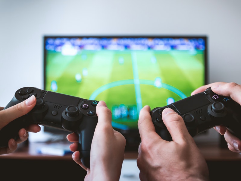 two controllers in human hands playing a football game on the ps5