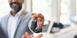 Ways to Get a Donated Car Closeup hand of cardealer giving new car key to customer. Detail of salesman hand giving keys to a client at showroom. Man's hand receiving car keys from african agent in a auto dealership with copy space.