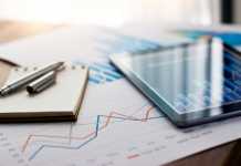 ONE: Helping Consumers Manage Finances and Simplify Their Lives Business document report on paper and tablet with sales data and financial business growth graph on table background.