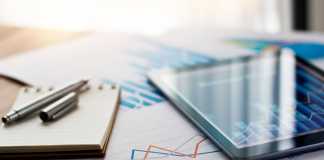 ONE: Helping Consumers Manage Finances and Simplify Their Lives Business document report on paper and tablet with sales data and financial business growth graph on table background.
