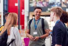 Group Of College Student Friends Meeting And Talking In Busy Communal Campus Building
