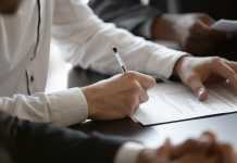 The Step-by-Step Guide to Getting a Business License in Dubai Close up young male employee manager customer hands signing paper contract after checking. Millennial investor client put signature at business agreement between partners. Editor making corrections.
