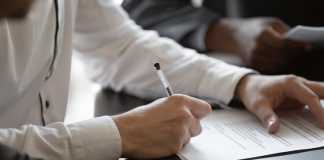 Close up young male employee manager customer hands signing paper contract after checking. Millennial investor client put signature at business agreement between partners. Editor making corrections.