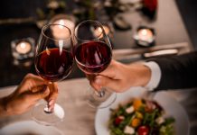 Close up of young couple toasting with glasses of red wine at restaurant