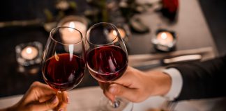 Close up of young couple toasting with glasses of red wine at restaurant