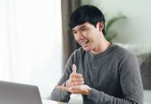 Young Asian man deaf disabled using laptop computer for online video conference call learning and communicating in sign language.