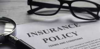 Selective focus of magnifying glass,glasses and Insurance Policy letter on a white wooden background.