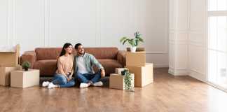 Family relaxing on floor in new home with cardboard boxes