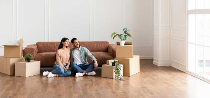 Family relaxing on floor in new home with cardboard boxes