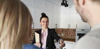 What is a Real Estate Broker? Rear view of agent gives the keys to the clients