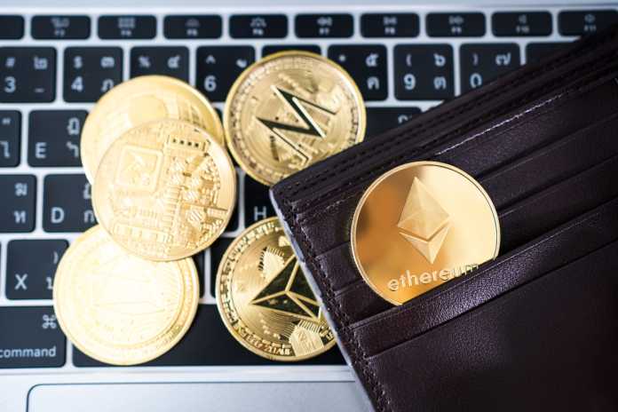 Metal golden Ethereum in brown leather wallet on laptop keyboard background. Cryptocurrency concept.