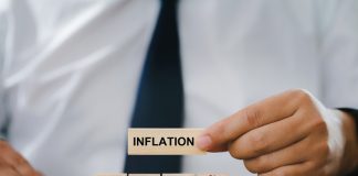 The Anatomy of Inflation Businessman Hand holding a wooden block with the word inflation. and wood block with sign percent and arrow up symbol. financial growth, interest rate increase, inflation concept