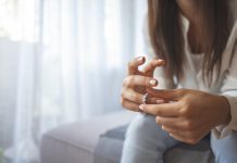 Unhappy woman holding wedding ring close up