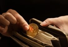 Bitcoin on the Move to the Next Crypto Revolution Woman puts gold bitcoin coin in her purse, close up hands shot