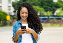 Beautiful brazilian young adult woman with retainer sending message with mobile phone