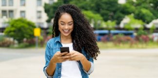 Beautiful brazilian young adult woman with retainer sending message with mobile phone