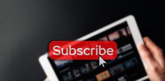 Subscription icon. Online video red subscribe button. Internet service on laptop digital tablet blured technology background. Social media concept. Streaming video.