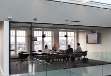 A team sitting at a conference table in an all-glass room discussing an account planning strategy.