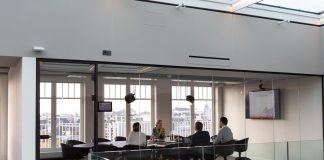 A team sitting at a conference table in an all-glass room discussing an account planning strategy.