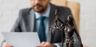 close-up view of lady justice statue and lawyer working working with papers behind