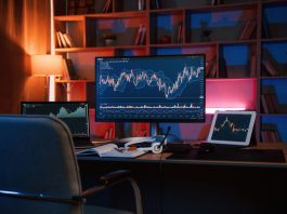 Learn How to Trade in 5 Simple Steps Computer with stock exchange graph on display is in the dark room with neon lighting