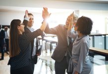 The Dynamic Formula For Corporate Success Smiling business colleagues high fiving each other in an office