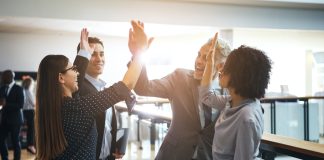 Smiling business colleagues high fiving each other in an office
