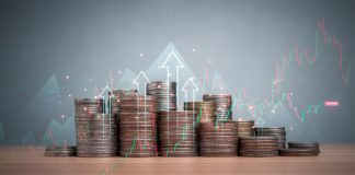 Coins are lined up on a wooden floor along with index charts, arrows and candlesticks. Represents financial, economic, business growth concepts. Financial success concept.