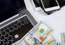 Laptop, money, credit cards and cellphone on wood background