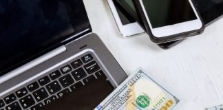 Laptop, money, credit cards and cellphone on wood background