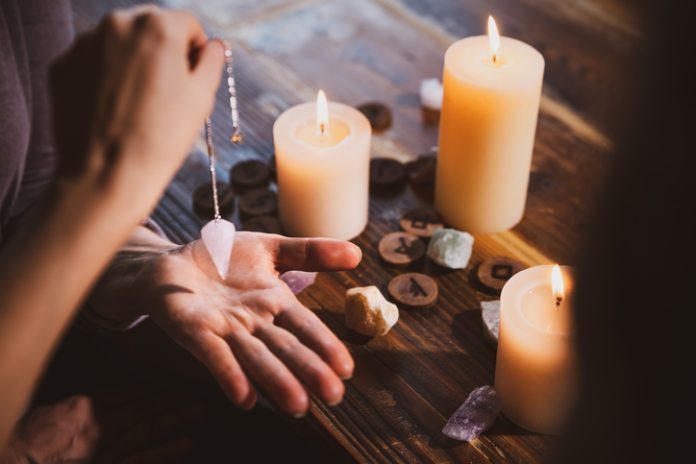 candles, stones and pendulum over the hand