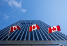 Three Canadian flags in front of a business