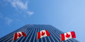 Three Canadian flags in front of a business