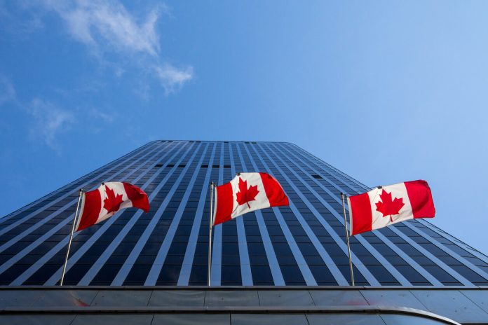 Three Canadian flags in front of a business