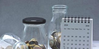 June 2024 calendar and glass jars with multicurrency coins. 2024 finance concept.