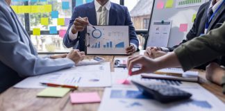 Group of confident business people point to graphs and charts to analyze market data