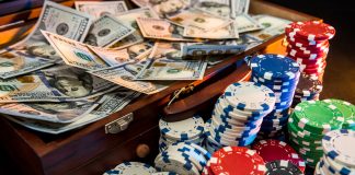 Colorful poker chips with playing cards and american dollars on dark background.