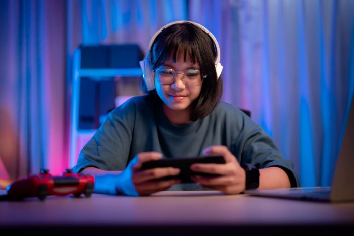 Asian girl playing game on phone at night having fun