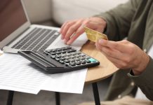 Man holding credit card while using calculator