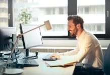 Guide to Test Automation and Codeless Testing Businessman Sitting on Black Rolling Chair While Facing Black Computer Set and Smiling