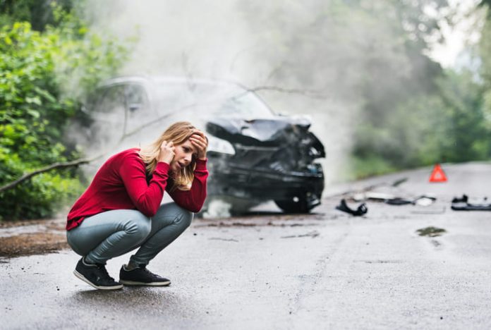 Woman making a phone call after a car accident