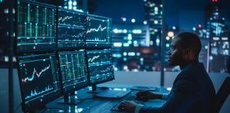 Financial Analyst Working on Computer with Multi-Monitor Workstation with Real-Time Stocks