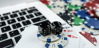 Online poker with laptop playing card chips and dice.