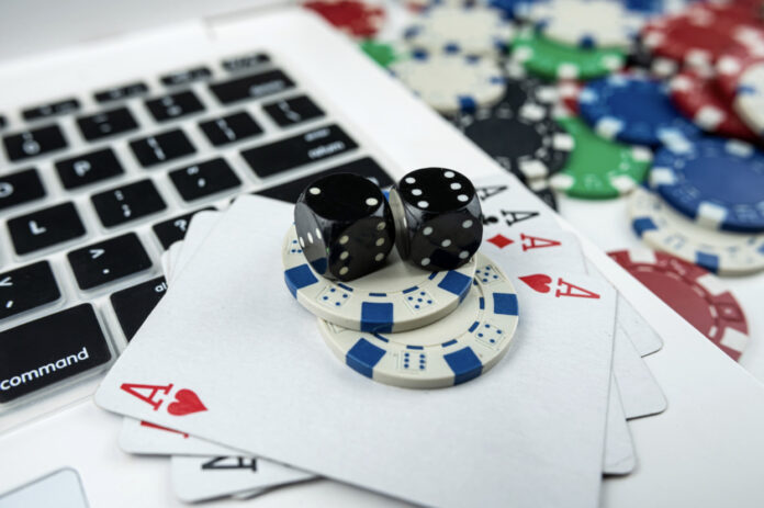 Online poker with laptop playing card chips and dice.