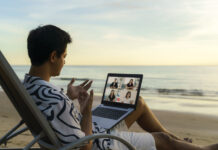 business man having remote video conference call with his business team at the beach during vacation