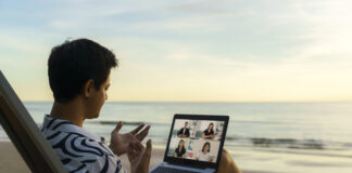 business man having remote video conference call with his business team at the beach during vacation