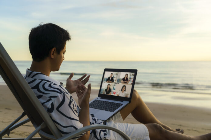 business man having remote video conference call with his business team at the beach during vacation