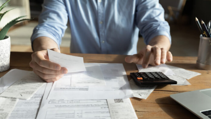 Young skilled man analyzing utilities household bills or taxes